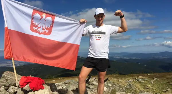Zdobywca Korony Polskich Gór z biało-czerwoną flagą na szczycie.