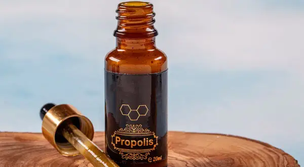 Krople propolisu na drewnianej desce. Dowiedz się, jak stosować propolis na jelita, by wesprzeć swoje zdrowie.