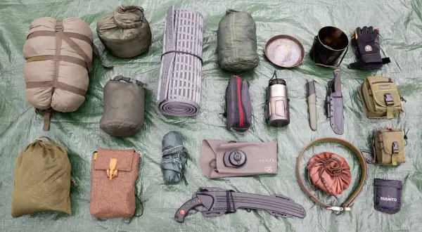 Outdoor-Ausrüstung: Schlafsack, Isomatte, Messer, Kochgeschirr, Handschuhe, Taschen und eine bpa-freie Trinkflasche.