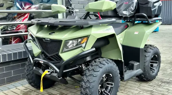 Zielony quad z bagażnikami, idealny na kategorię B. Wygląda na solidną maszynę do jazdy terenowej.