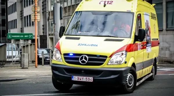 Ambulance jaune, véhicule prioritaire, roule en ville. Les gyrophares bleus clignotent.