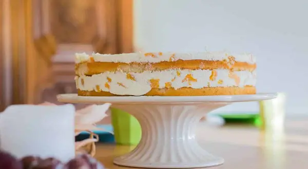 Ein leckerer no bake kuchen mit Sahne und Fruchtstücken auf einem Tortenständer.