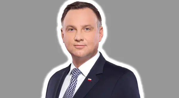 Prezydent Andrzej Duda w garniturze, z biało-czerwoną flagą na klapie. Jego twarz wyraża powagę, jakby rozważał kwestię ułaskawienia.