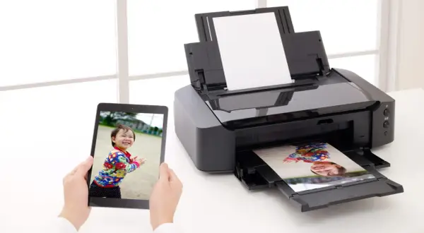 Jak dobra? papier fotograficzny do drukarki? Dziecko uśmiecha się na tablecie, a jego zdjęcie wychodzi z drukarki.
