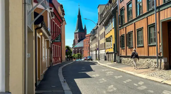 Ulica w Oslo z kolorowymi kamienicami i kościołem w tle.