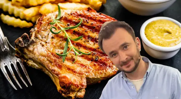 Pyszny schab z kością, grillowany z rozmarynem, podany z frytkami i musztardą. Uśmiechnięty mężczyzna w tle.