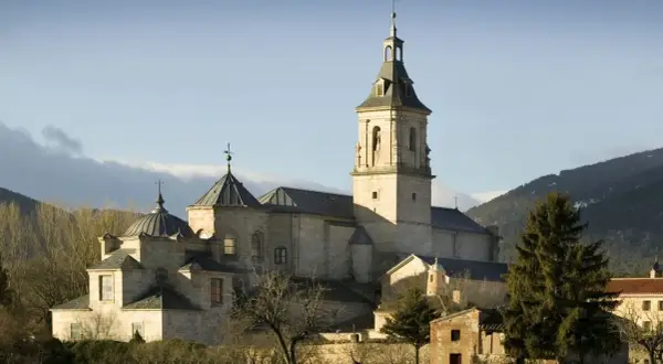 El imponente monasterio del Paular se alza bajo un cielo azul, con sus cúpulas y campanario de piedra bañados por el sol.