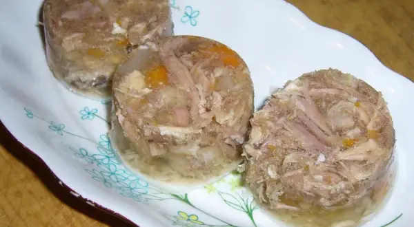 Trzy okrągłe porcje galarety z nóżek wieprzowych, z widocznym mięsem i warzywami. Idealne do nauki, jak gotować galaretę z nóżek wieprzowych.