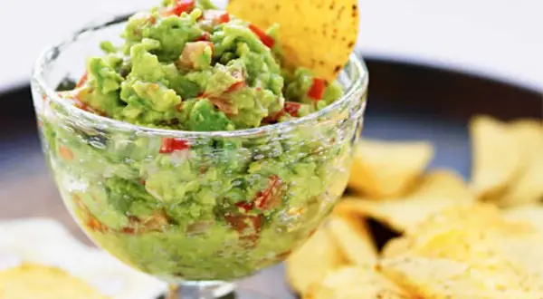 En skål med krämig guacamole, perfekt för ditt nästa guacamole recept. Serveras med tortillachips.