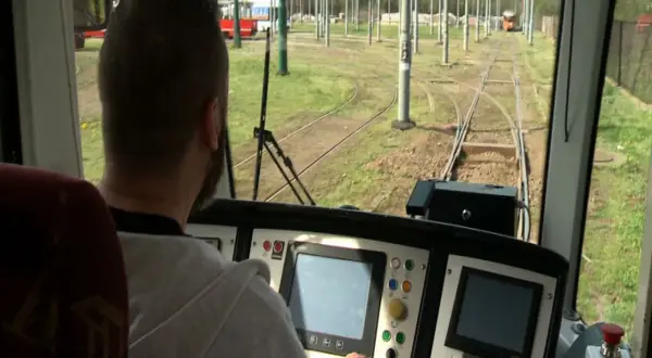 Mężczyzna za sterami tramwaju, być może uczestnik darmowego kursu na maszynistę, obserwuje tory.