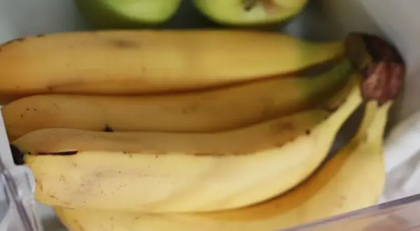 Pęk bananów w lodówce, obok zielonych jabłek. Czy banany można trzymać w lodówce? Tutaj są dowody.