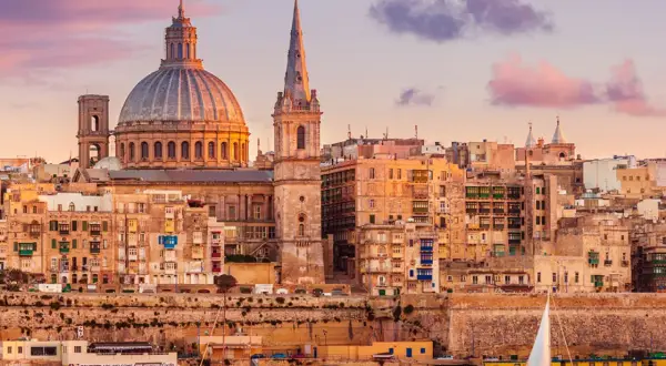 Sonnenuntergang über Valletta, Malta. Die Kuppel der St. Paul's Cathedral und Segelboote spiegeln sich im Wasser. Tolle Urlaub in Malta Erfahrungen!
