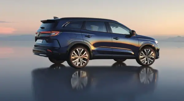 Granatowy Renault Espace 2024 z odbiciem na wodzie, na tle zachodzącego słońca.