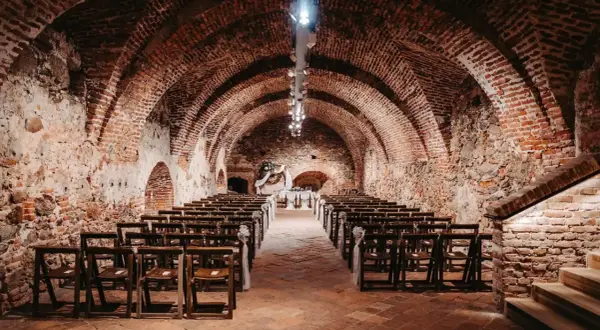 Historische Gewölbe des Kulturvereins Glems, bereit für eine Zeremonie mit Reihen von Holzstühlen und einem festlichen Altar.
