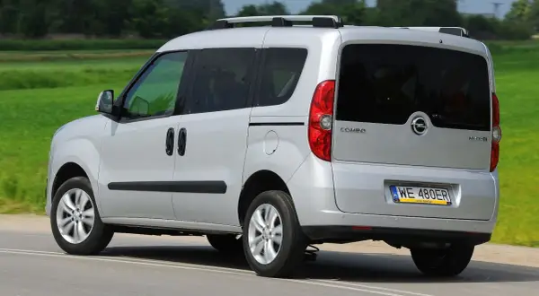 Srebrny Opel Combo C w ruchu, z tyłu widoczny bagażnik dachowy i przyciemniane szyby.