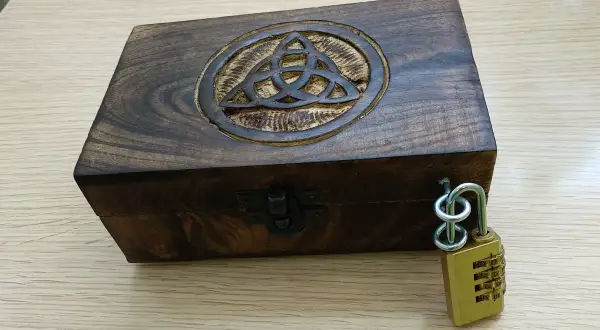 Caja de madera con símbolo celta y candado de combinación, lista para un escape room matematicas.