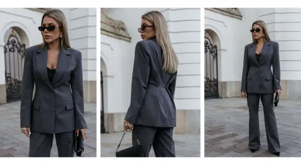 Elegancka kobieta w szarym garniturze, prezentująca styl minimalistyczny ubiór. Czarna koronkowa bluzka i okulary dodają charakteru.