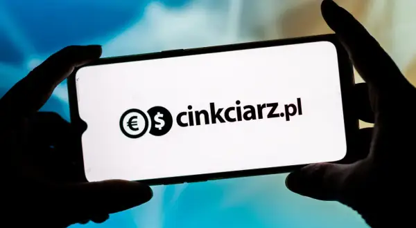 Dłonie trzymają smartfon z widocznym logo i nazwą "cinkciarz.pl". To portal, który ułatwia wymianę walut, jak Conotoxia.