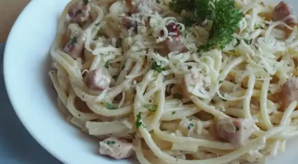 Spaghetti carbonara - przepis oryginalny ze śmietaną. Pyszne danie z makaronem, boczkiem i serem, udekorowane natką pietruszki.