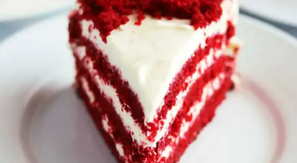 En saftig bit red velvet cake med krämig frosting och smulor på toppen.