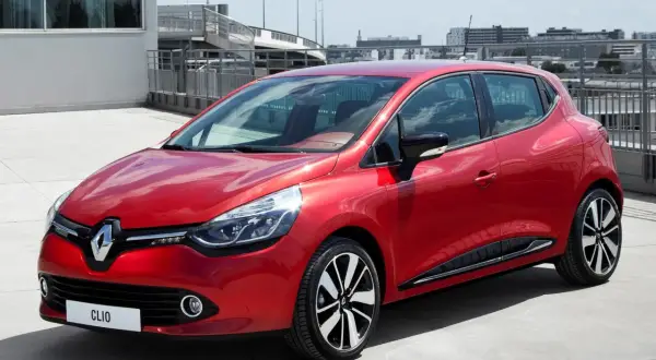 Czerwone Clio 4 RS błyszczy na betonie, gotowe do dynamicznej jazdy.