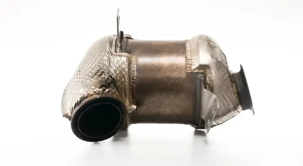 Metalowy element układu wydechowego, przypominający kształtem tłumik lub fap, z widocznymi zgrubieniami i mocowaniami.