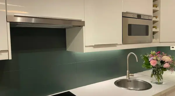 Crédence cuisine vert foncé, une idée pour quelle peinture pour carrelage mural cuisine ? Évier, hotte, four, bouquet de fleurs.