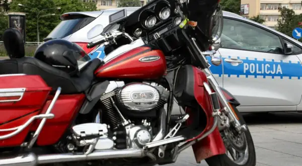 Czerwony motocykl Harley-Davidson obok radiowozu. Czyżby ktoś próbował jeździć bez prawa jazdy?