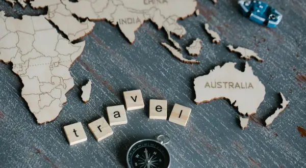 Drewniana mapa świata z napisem "AUSTRALIA" i literami "travel". Ciekawe ciekawostki o Australii czekają na odkrycie!
