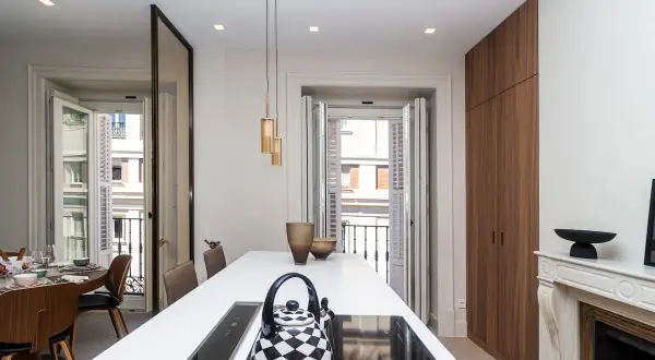 Cocina moderna con isla blanca, tetera a cuadros y vistas a balcón. Un buen lugar para vivir, pero ¿cuánto cuesta un alquiler en Madrid?