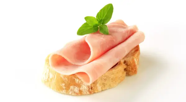 Kanapka z szynką i masłem, ozdobiona listkiem mięty. Zastanawiasz się, ile kalorii ma kanapka z szynką i masłem?