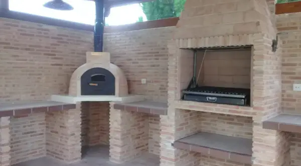 Un barbecue in muratura fai da te con forno a legna e griglia, perfetto per cene all'aperto.