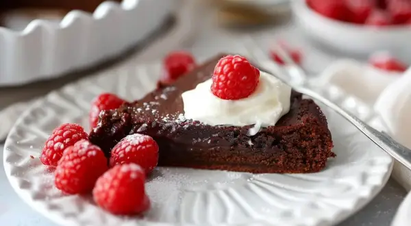 En bit kladdkaka med vispad grädde och hallon, perfekt för ett kladdkaka recept.