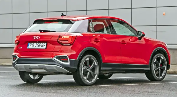 Czerwone Audi Q2 z polskimi tablicami PO 2SP89. Kompaktowy SUV, którego wymiary sprawiają, że jest idealny do miasta.