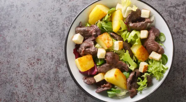 Salade de gésiers savoureuse avec pommes de terre rôties, croûtons et salade verte. Un délice pour les papilles.