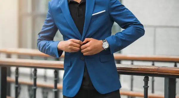 Mann im blauen Anzug und schwarzem Hemd, der seinen Anzug zuknöpft. Elegante Kleidung für einen besonderen Anlass.