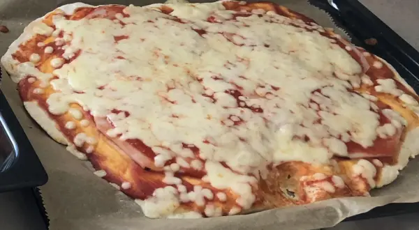 Domowa pizza z szybkim przepisem na ciasto, pokryta sosem pomidorowym i rozpływającym się serem. Idealna na szybki obiad.