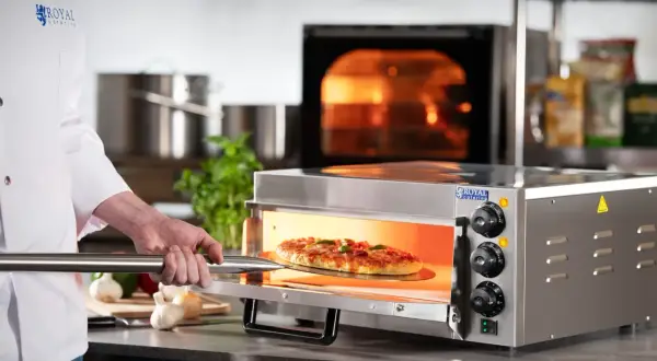 Szef kuchni wyjmuje pizzę z rozgrzanego piekarnika. Dowiedz się, jak ustawić piekarnik na pizzę, by uzyskać idealny efekt.