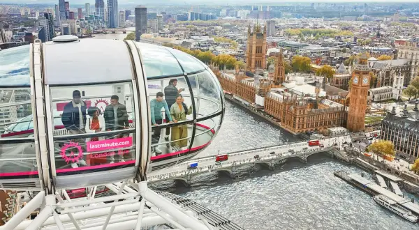 Ludzie podziwiają panoramę Londynu z kapsuły diabelskiego młyna. Widać Tamizę, Parlament i Big Bena.