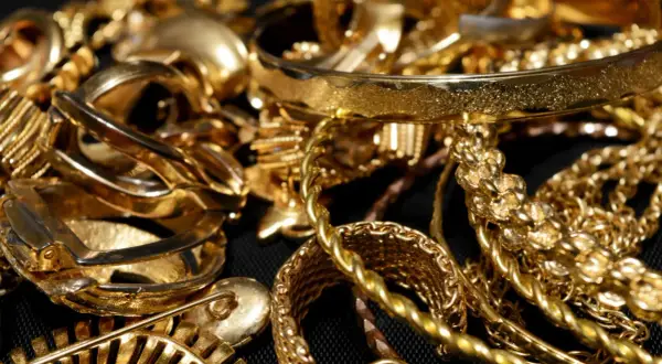 Stos błyszczącej biżuterii, w tym bransolety i łańcuszki, symbolizuje cenne złoto LBMA.