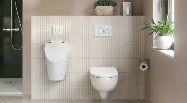 Dwa wiszące WC, jedno wyżej, drugie niżej, pokazują różnice w wysokości WC od podłogi. Obok prysznic i uchwyt na papier.