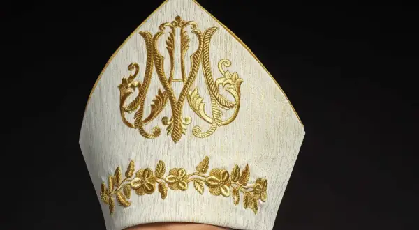 Biała mitra z haftem w kolorze złota, symbolizująca godność. Warto wiedzieć, jak się zwracać do biskupa, by okazać mu szacunek.