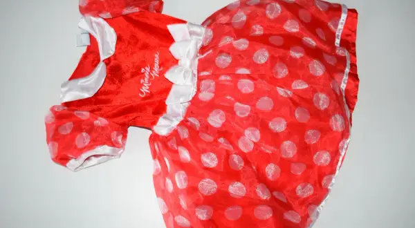 Czerwona sukienka w białe grochy, ozdobiona kokardkami i napisem "Minnie Mouse". Idealne myszka minnie przebranie dla małej fanki.