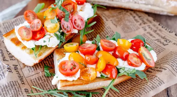 Geröstetes Brot mit Burrata, Kirschtomaten und Rucola.