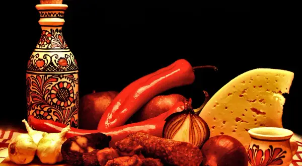 Tradycyjne węgierskie smaki: papryka, kiełbasa, ser i ozdobna butelka.