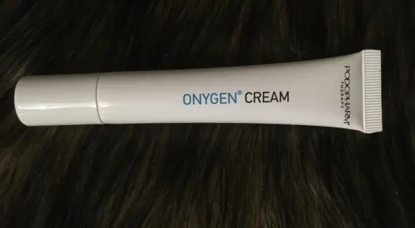 Biała tubka kremu OXYGEN CREAM na ciemnym, futrzanym tle.