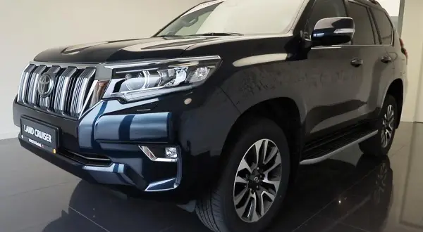 Ciemnogranatowy Land Cruiser Prado z chromowanym grillem i reflektorami LED, gotowy na każdą przygodę.