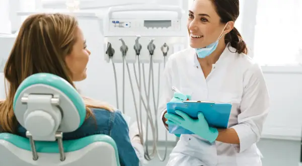 Uśmiechnięta dentystka omawia z pacjentką efekty leczenia aparatem ortodontycznym.
