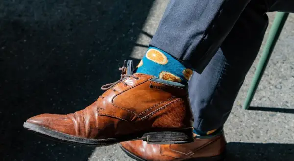 Niebieskie skarpetki w pomarańcze dodają charakteru do eleganckiego garnituru. Idealne pytanie: jakie skarpetki do garnituru?