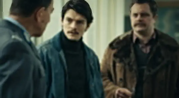 Trzech mężczyzn w rozmowie, jeden w mundurze. Atmosfera napięcia, jak w filmie "Hiacynt".